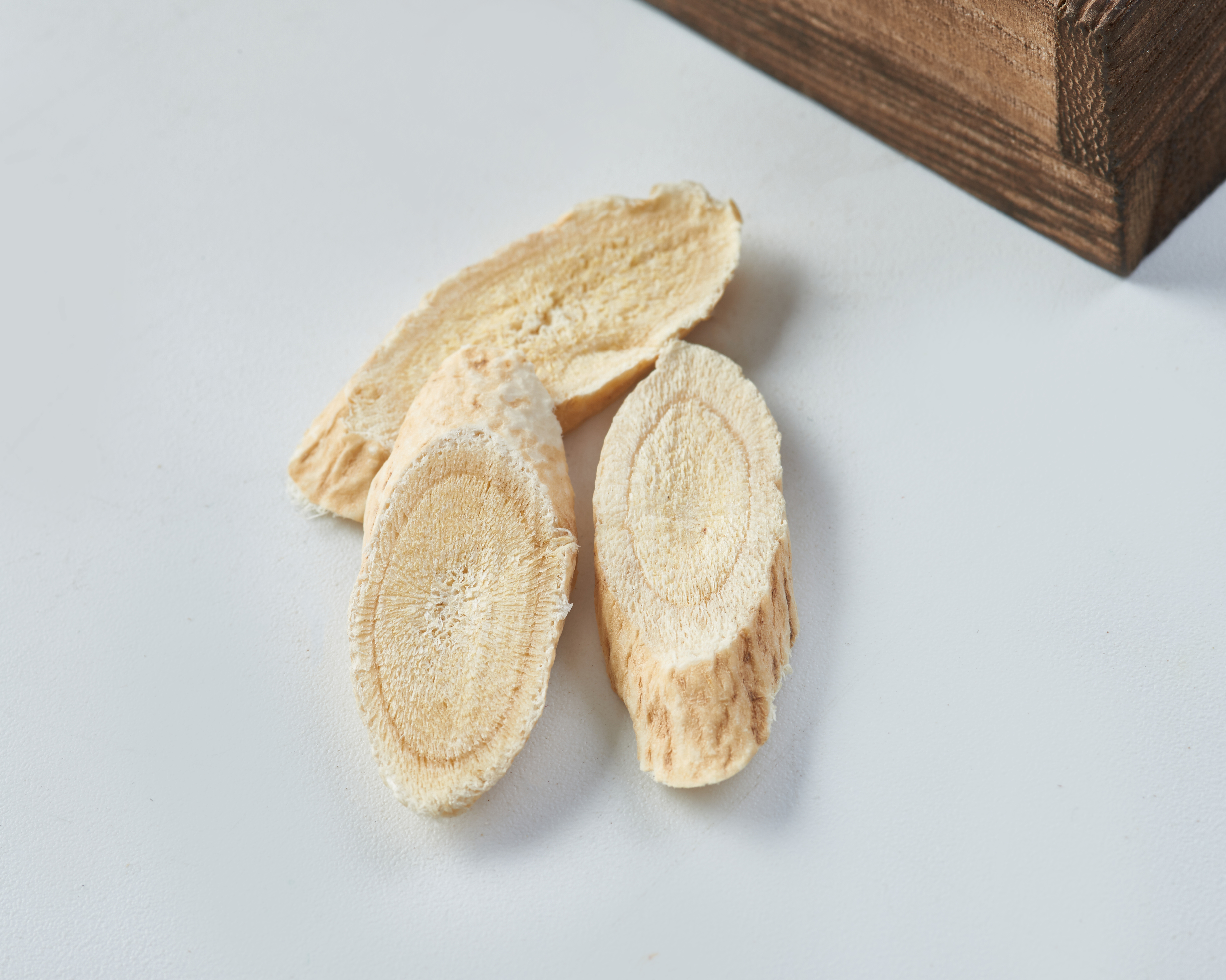 展示几根完整的干制黄芪药材,表面呈淡黄色至深黄色,质地坚硬,切片可见明显的纤维纹理 黄芪干品特写