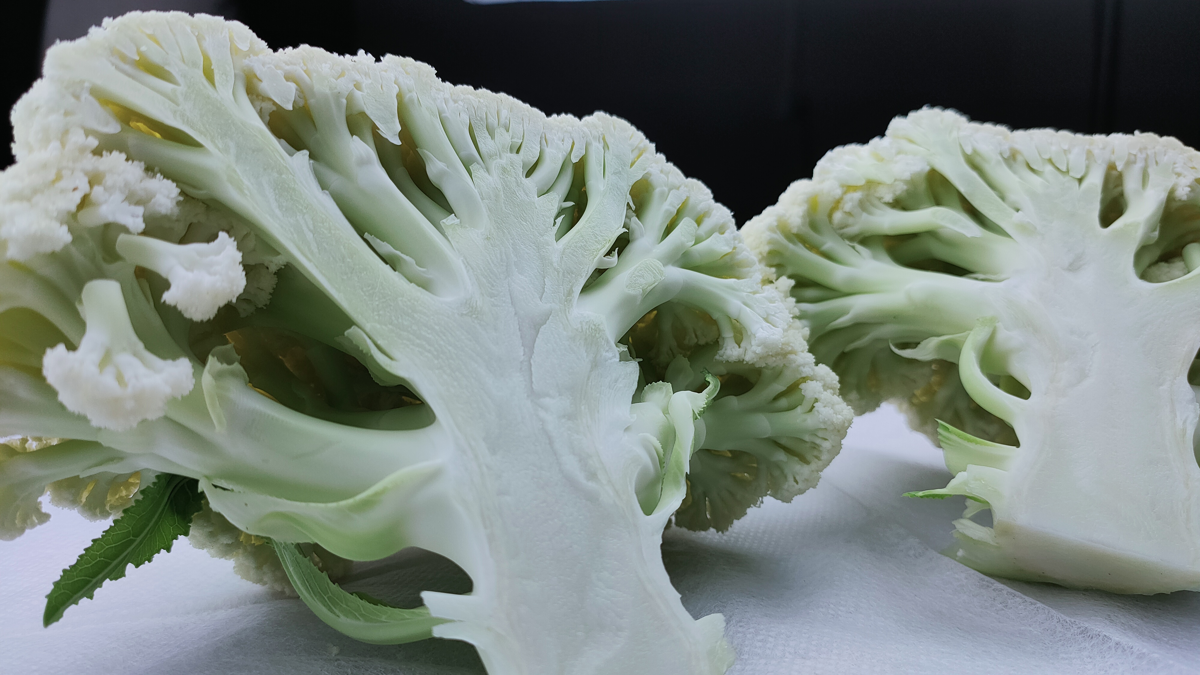 一盘刚出锅的清炒松花菜摆放在原木色餐桌上,花球完整分明,表面泛着淡淡油光,点缀着绿色葱段和红色干辣椒碎片,背景虚化的碗筷显示家庭用餐场景,整体构图温馨自然 清炒松花菜成品特写