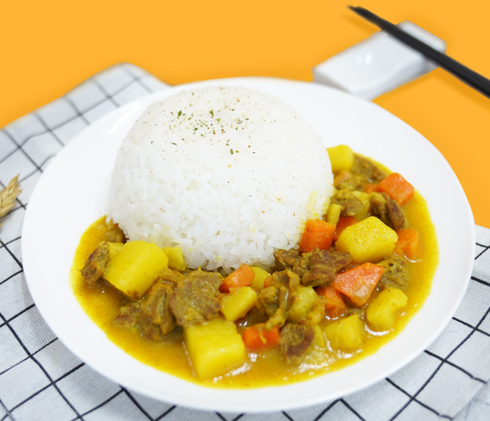 一碗热腾腾的咖喱饭,旁边配有米饭和配菜 成品咖喱配米饭