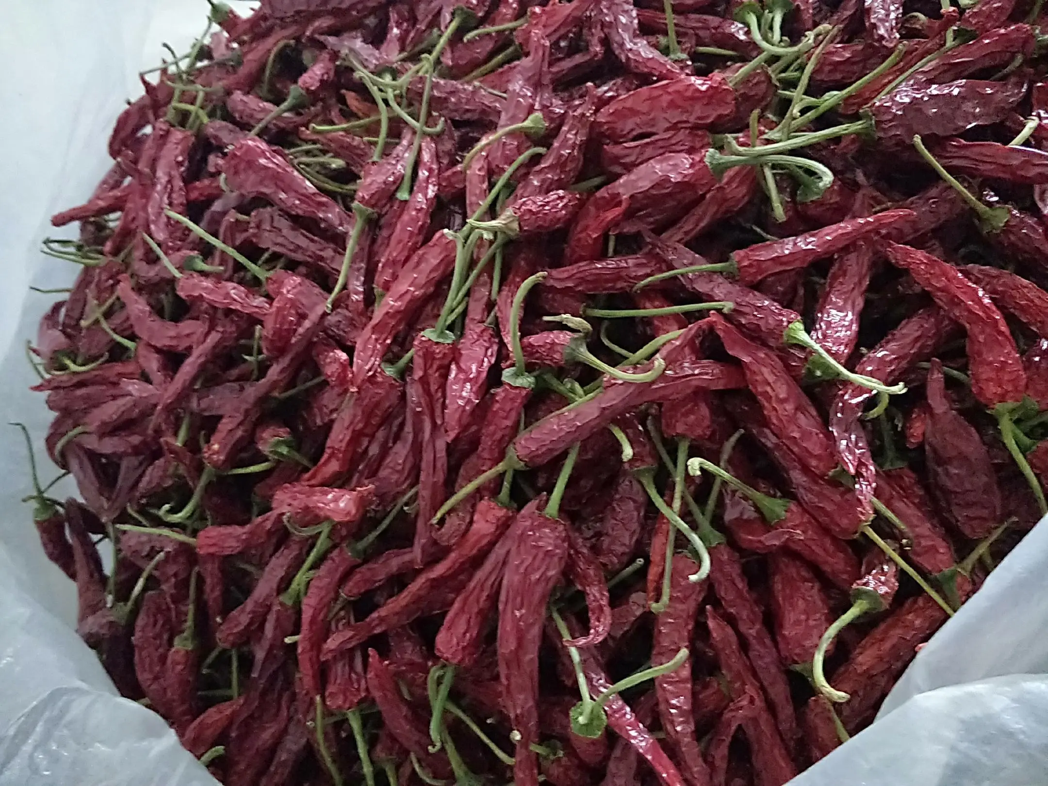 手工辣椒面成品特写：深红色粉末细腻均匀，略有芝麻颗粒闪现，盛于粗陶碗中，旁置竹勺与小碟盐粒、花椒粉