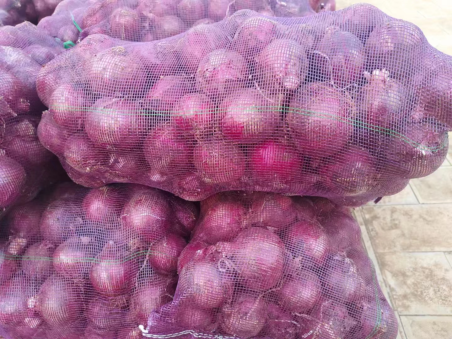 现代化蔬菜加工车间内,工人正在对元葱紫皮进行光电分选和自动称重包装,传送带上排列整齐的紫色洋葱色泽一致,背景有冷链仓储标识和质检台,展现标准化加工流程 元葱紫皮分拣包装车间实景图