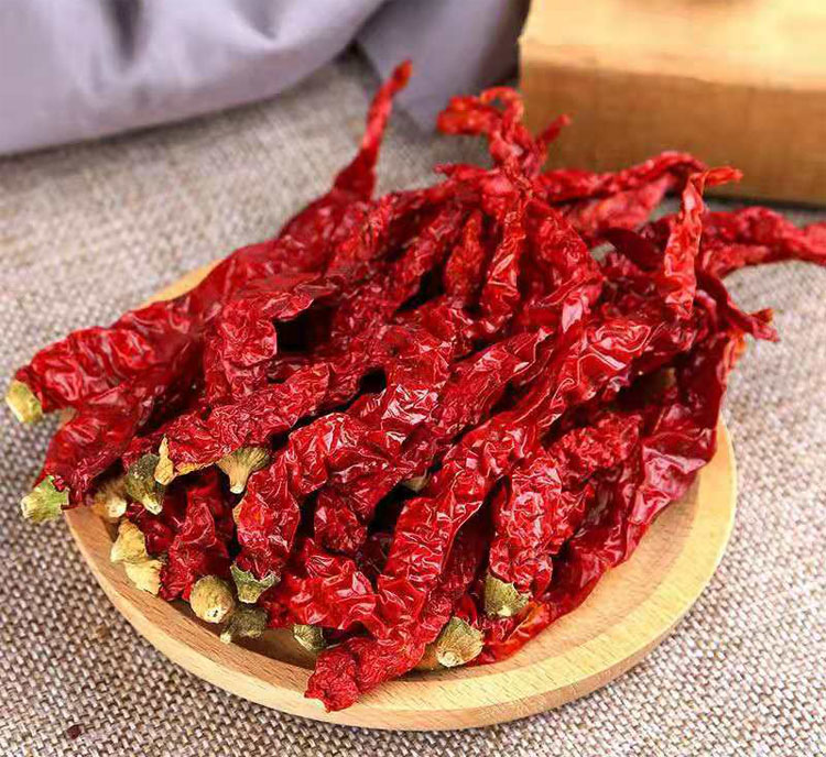 一盘色泽红亮、完整干燥的干货干辣椒平铺在木质案板上,部分已碎成小段,背景为传统农家晾晒场景,阳光洒落,体现自然风干工艺 干货干辣椒特写