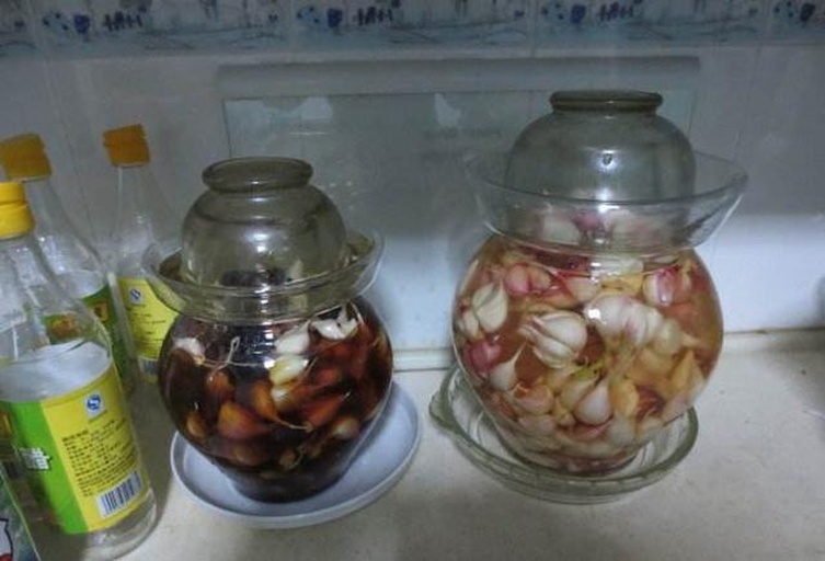 玻璃密封罐中装满切好的蒜苗，正在倒入透明腌料汁