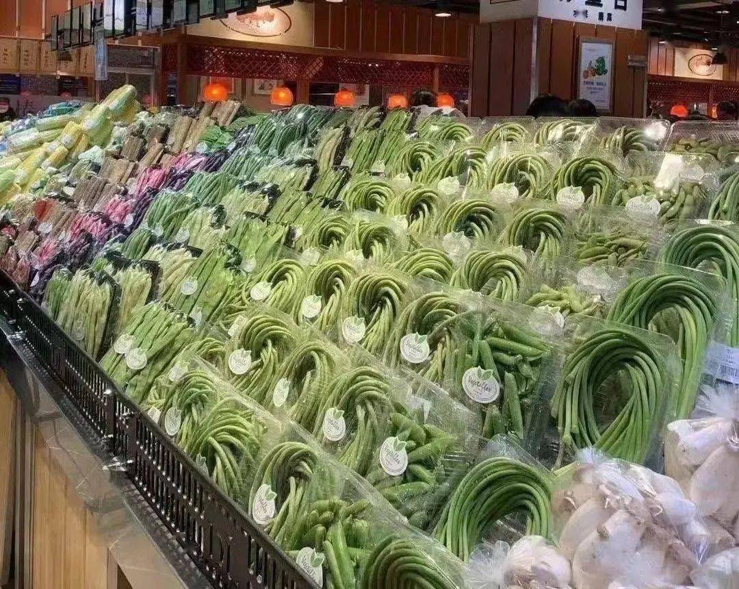 超市货架上整齐摆放的新鲜豆角与芹菜商品陈列
