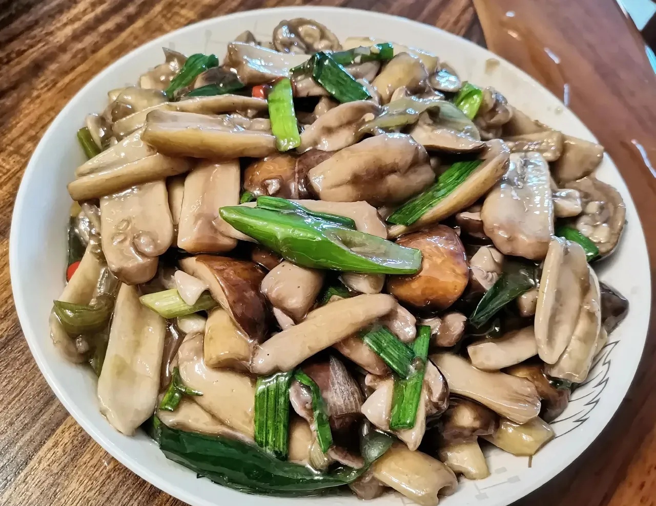 展示清炒平菇的制作过程,锅中翻炒的平菇色泽鲜亮,配以葱花点缀 清炒平菇烹饪过程图