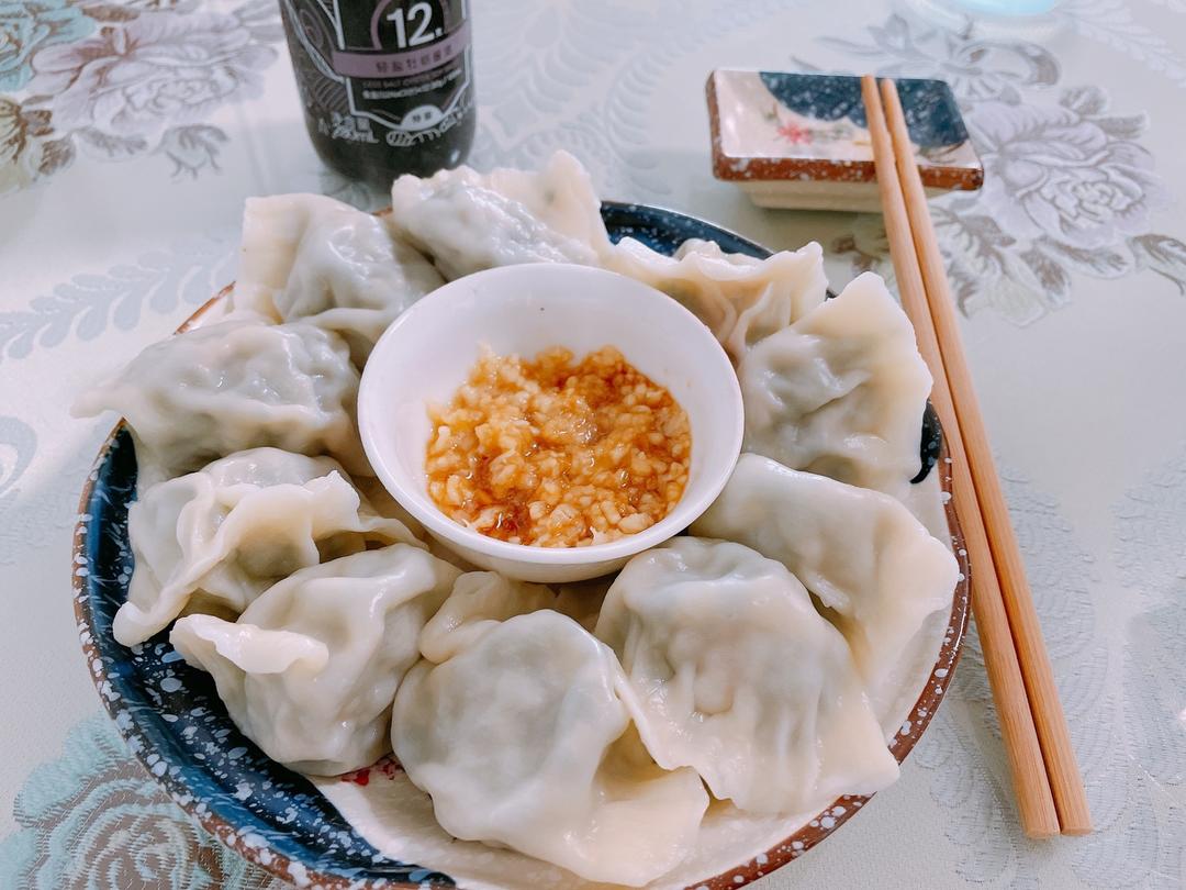 一家人围坐在餐桌前吃热气腾腾的豆角肉饺子，桌上摆着醋碟和蒜泥，氛围温馨