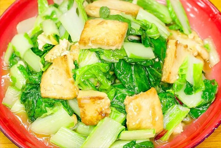 小白菜幼苗豆腐羹成品图,展现细腻质地与天然色泽,体现‘老幼皆宜’的食用场景 餐桌摆盘:青瓷碗中盛放翠绿的小白菜幼苗豆腐羹,表面浮着嫩黄蛋花与细嫩豆腐丁,撒少量枸杞与香葱末,热气氤氲