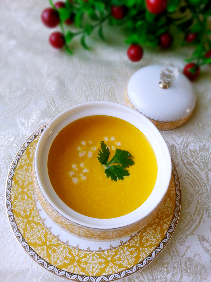 白色陶瓷碗中盛着金黄色的糯玉米浓汤,表面泛着奶白色光泽,旁边放着一小片面包和木勺,背景为秋日窗台,阳光洒入 一碗热腾腾的糯玉米浓汤