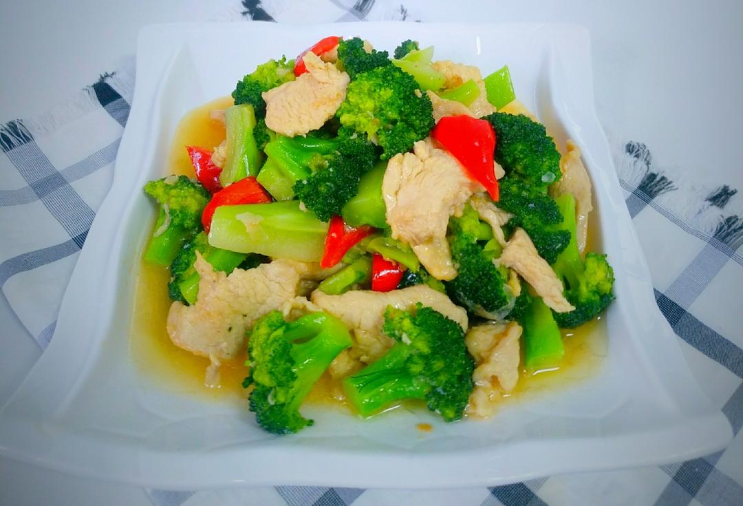 不粘锅内鸡胸肉与西兰花正在翻炒,锅气升腾,蒜片点缀其间,色泽清新,鸡胸肉呈乳白色,西兰花为鲜绿色,整体干爽无多余汤汁 西兰花与鸡胸肉合炒