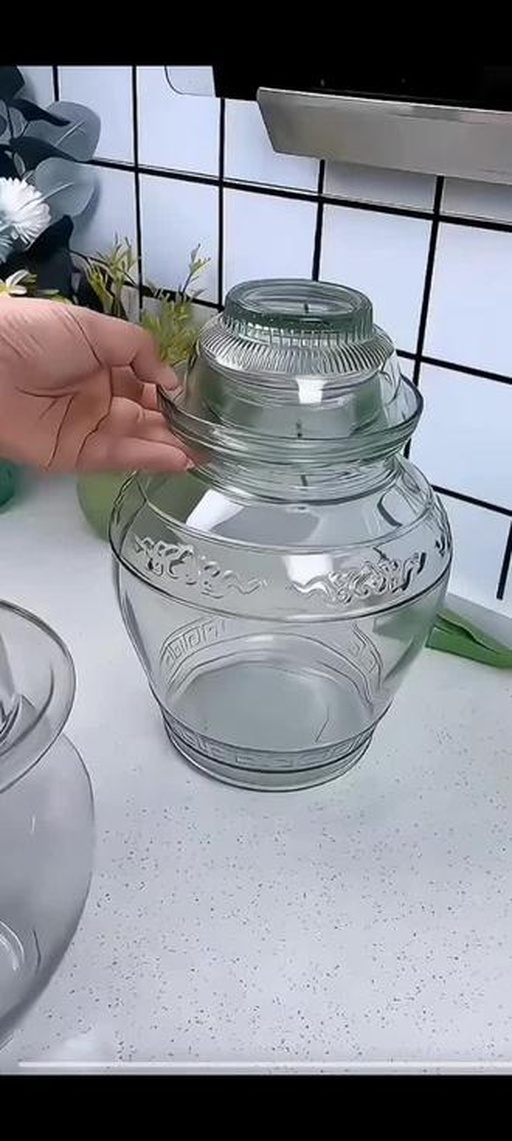 传统玻璃泡菜坛密封发酵状态特写,水封槽内清水满盈,坛体洁净无霉斑,放置于阴凉避光橱柜中,体现安全可控的发酵环境 泡菜坛密封发酵实景:深褐色玻璃坛置于木质橱柜阴影处,水封槽内清水清晰可见,坛沿洁净无霉斑,背景虚化突出坛体质感