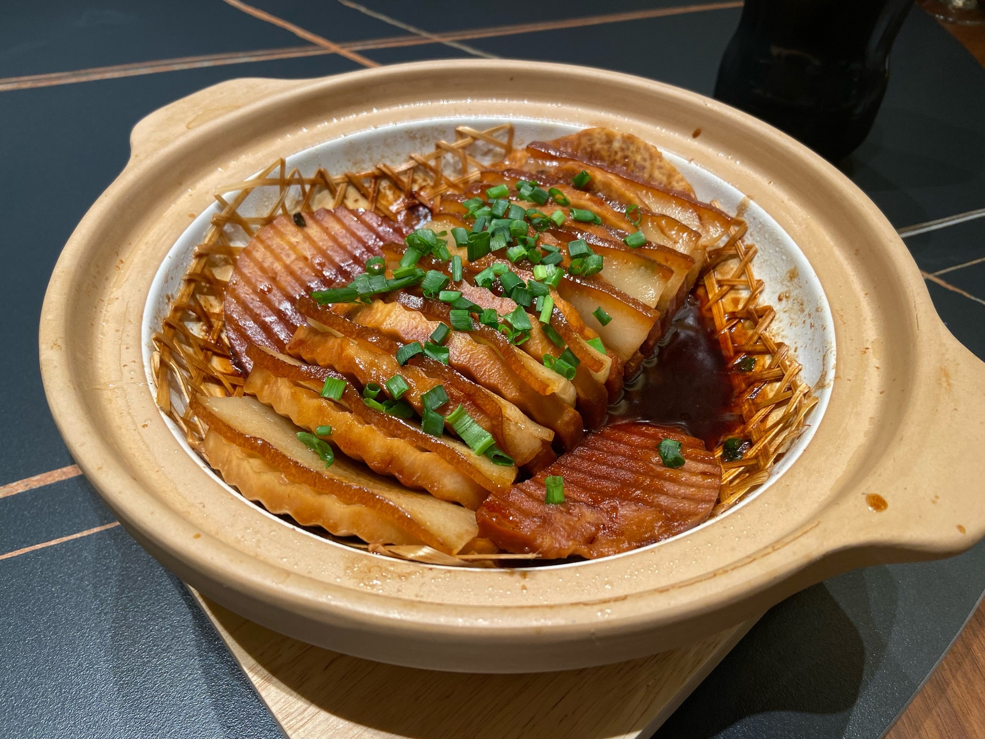 子姜红烧肉成品特写：油亮琥珀色五花肉块堆叠，表面裹着浓稠酱汁，嵌着半透明金黄子姜片，几粒完整八角点缀其间，背景为青灰粗陶钵与竹筷