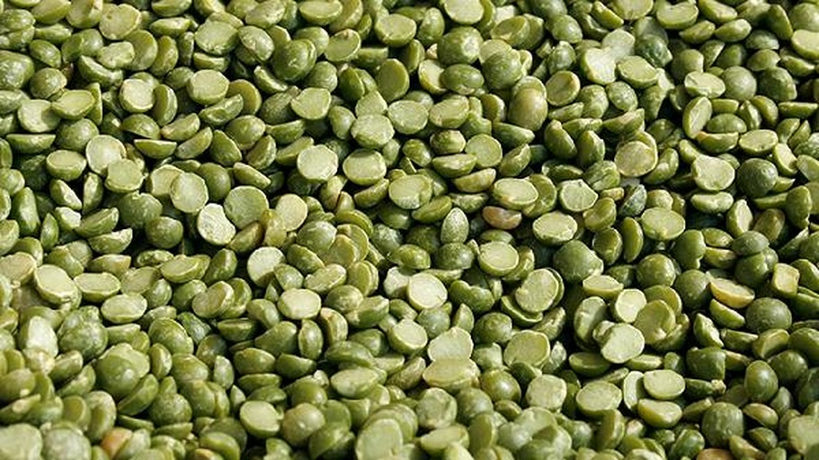 画面展示左侧为泡发后的浅黄色干豌豆,右侧为新鲜剥出的绿色豌豆粒,背景为白色瓷碗与竹筷,突出食材原生态质感 干豌豆与鲜豌豆对比图