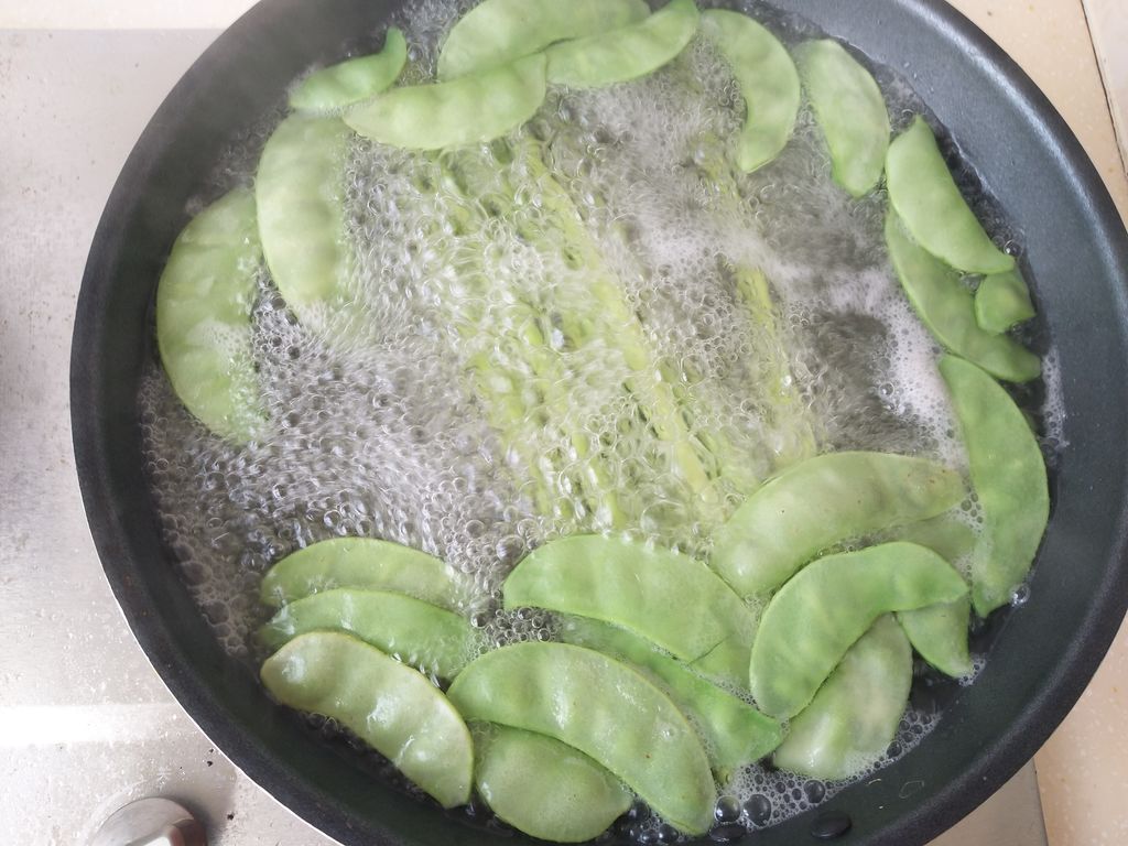 青豌豆正在沸水中焯烫,锅中加入少许盐和油 青豌豆焯水过程