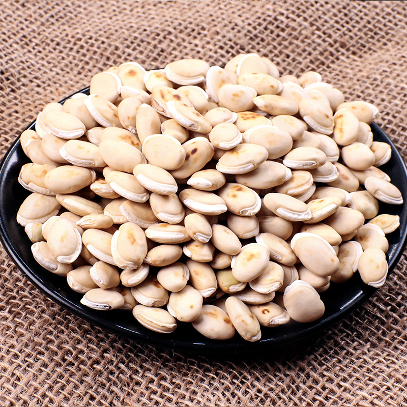 两种豆类并列摆放,左侧为普通扁豆(颜色偏褐或紫黑),右侧为白扁豆(外壳洁白光滑),背景为木质砧板,旁边配有放大镜突出细节差异 扁豆与白扁豆对比图