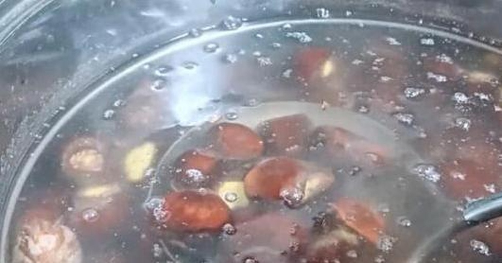 一位厨师正在将皮皮枣倒入沸腾的水中进行焯烫处理,旁边放置一碗冰水用于快速冷却,台面上摆放着去皮前后的对比样本 热水烫泡法操作示意图