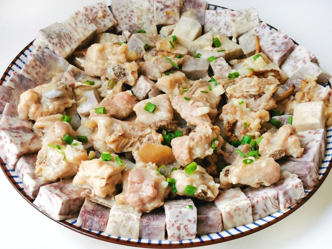 一张摆放在木桌上的传统菜肴照片,包括蒸芋头、芋头炖排骨和一盘绿色炒菜(象征处理过的芋头杆),背景为乡村厨房环境,营造出自然健康的饮食氛围 传统农家菜中的芋头料理