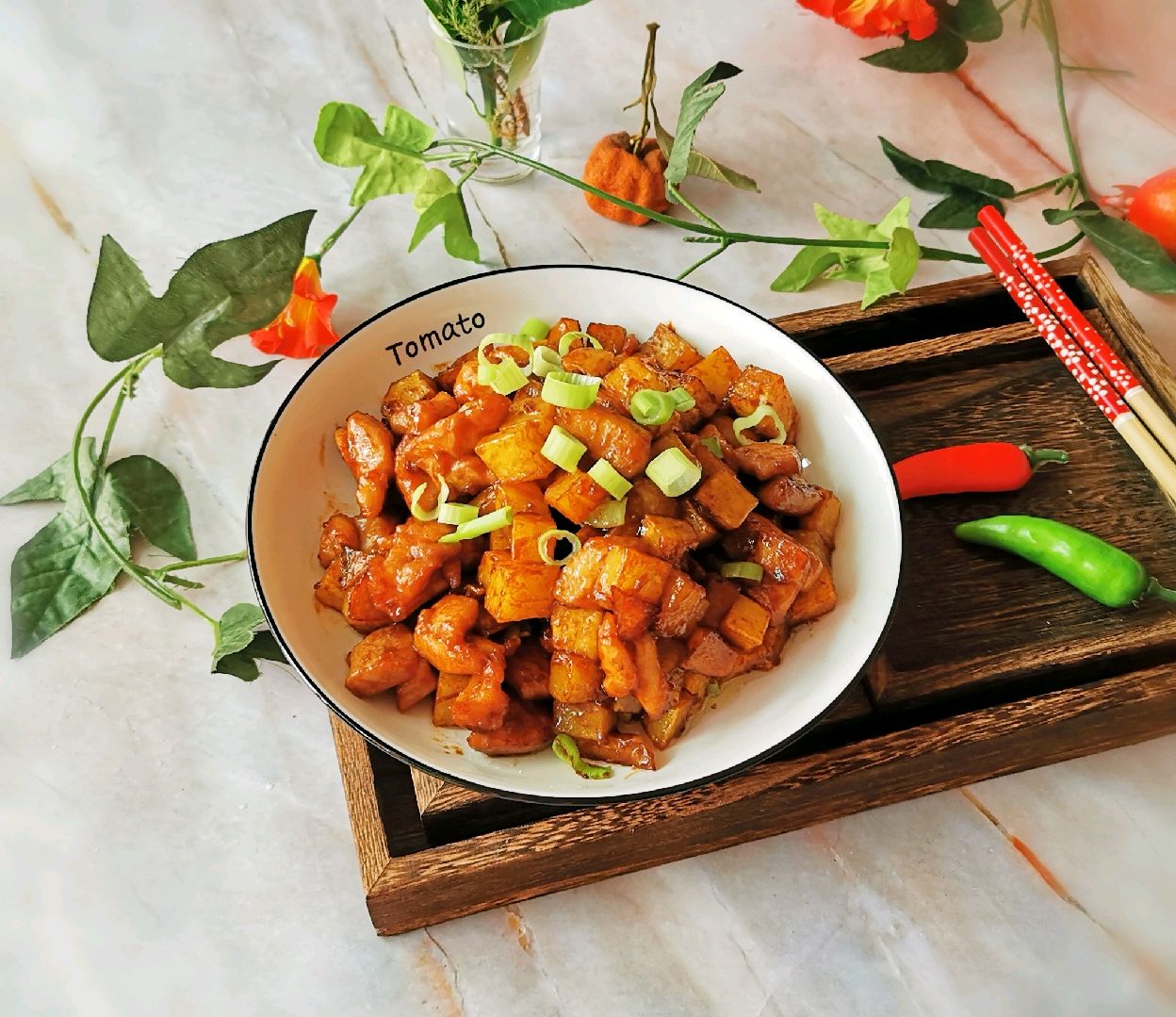 中式炒锅中正在烹制西红柿与土豆混合菜肴,食材颜色鲜艳,体现家庭烹饪场景,适合用于菜谱或营养搭配说明 一锅正在灶台上翻炒的西红柿土豆块,锅中食材呈金红色泽,蒸汽升腾,配有青椒片和蒜末点缀