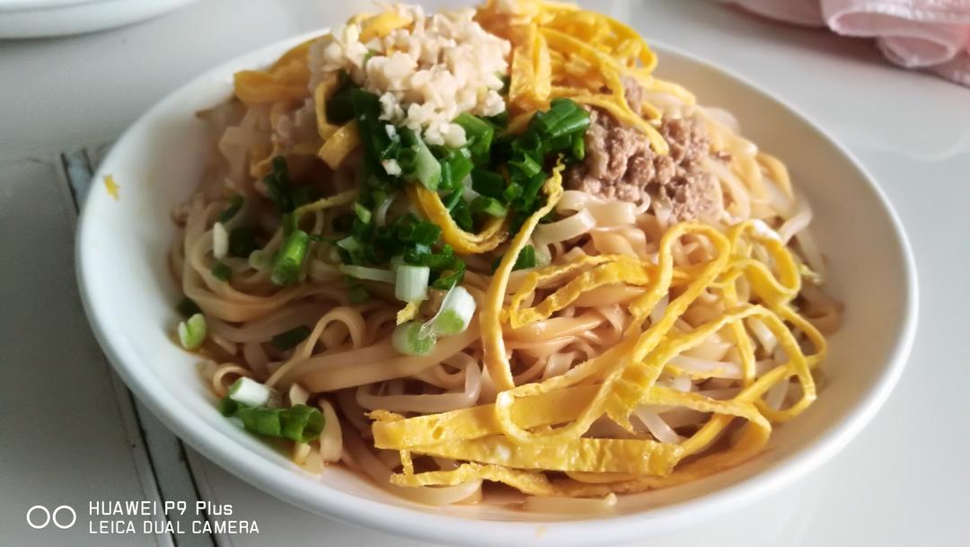 一碗煮熟的姜面条盛放在白色瓷碗中,面条呈淡黄色,表面泛着油光,配有葱花、青菜和卤蛋,旁边放置一小碟红醋蘸料,整体呈现温暖诱人的家常风味 姜面条成品展示