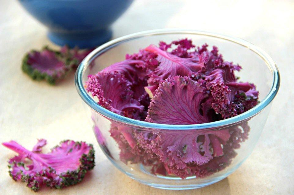 一个透明玻璃保鲜盒中装着半满的凉拌紫甘蓝,盒子盖紧放置在冰箱冷藏格中,周围有其他蔬菜和酸奶瓶,背景虚化突出食物储存环境的整洁与低温状态 厨房冰箱内存放凉拌菜场景