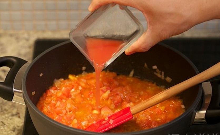 厨师正在用搅拌棒在锅中将炖煮后的番茄混合物打成细腻的红色浓汤