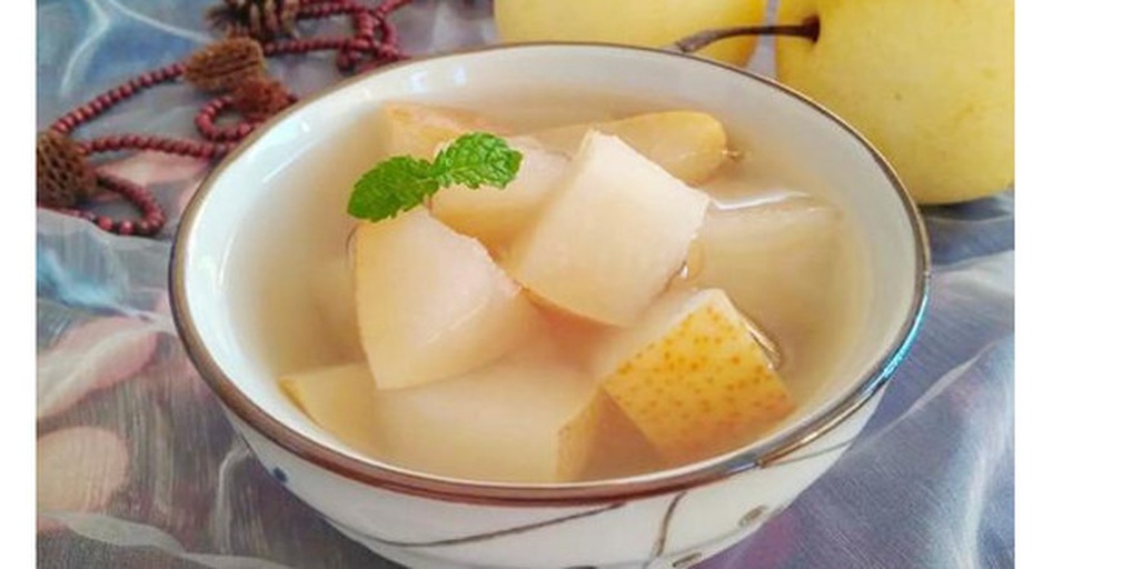 生活化场景图:新鲜雪花梨果肉块装于透明玻璃碗,色泽莹白,汁水丰盈,佐以翠绿薄荷与浅褐杏仁碎,传递‘低热量、高颜值、即食营养’的现代健康饮食主张 雪花梨科学食用场景:玻璃碗中盛放新鲜雪花梨块(去皮去核)、搭配薄荷叶与少量坚果碎,背景为厨房台面,体现健康轻食理念