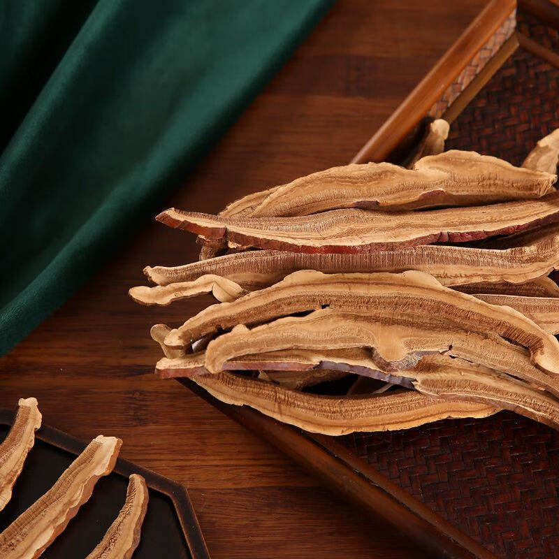 一盘浅棕色的天然灵芝切片整齐排列在木质托盘上,每片厚度均匀,表面有自然纹理和光泽,背景为柔和的自然光环境,突显其天然与高品质特征 灵芝切片特写