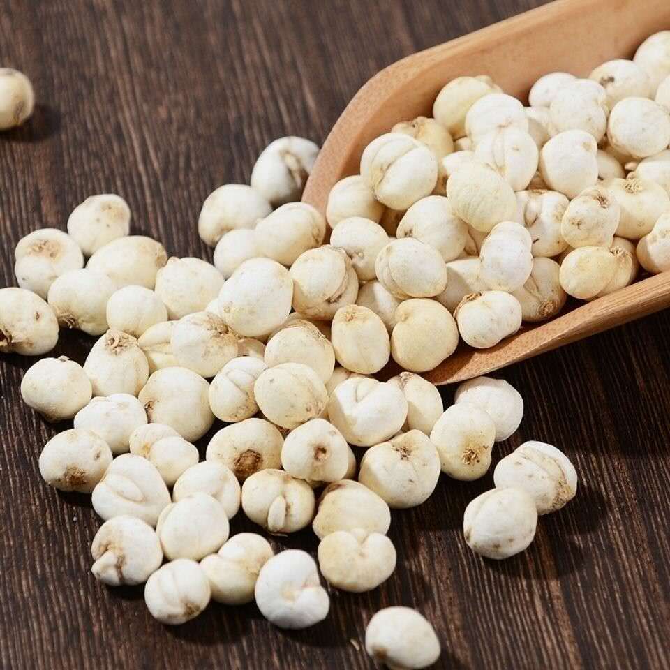 一张高清图片,显示一台白色电子厨房秤上放置着一堆浅白色的干莲子,显示屏清晰可见数字‘25.0’,旁边摆放一把不锈钢小勺和一小袋未开封的莲子,背景为浅色料理台面 莲子与厨房秤搭配展示