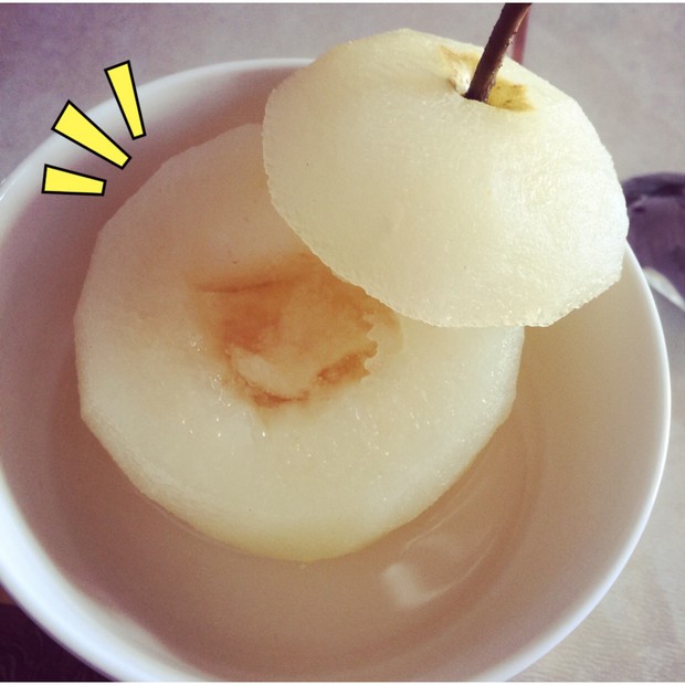 透明玻璃密封罐中盛满琥珀色腌渍液,里面浸泡着切成月牙状的酸梨块,液体清澈透亮,可见底部沉淀的冰糖晶体和散落的花椒、八角香料,罐体标签标注‘酸醋梨-第3天’ 玻璃罐中浸泡的酸醋梨