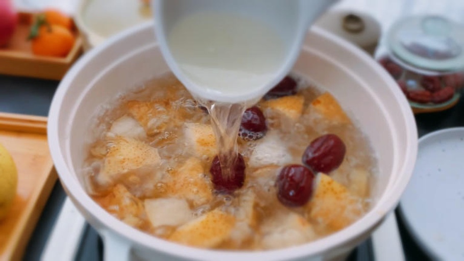 炖锅中酸梨汤正在小火慢炖,梨块已变软,汤色微黄 酸梨汤炖煮过程图