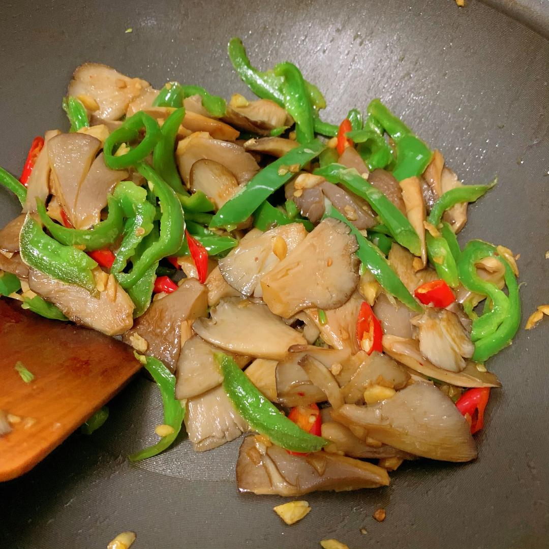 俯拍高清图:青翠子姜丝缠绕琥珀色杏鲍菇条,点缀红椒丁,油润光亮无水汽,锅底可见零星焦糖化酱汁斑点,木质砧板背景 子姜炒蘑菇出锅特写
