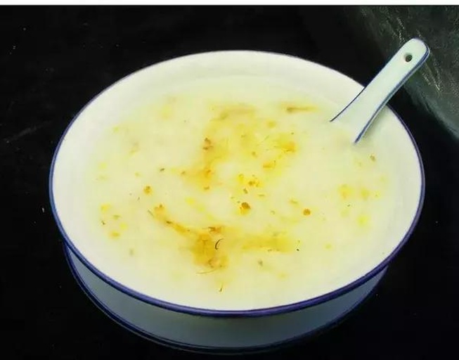 砂锅中正在熬煮的白菜粥，米粒已开花，黄心白菜帮与叶清晰可见，表面泛着淡淡油光