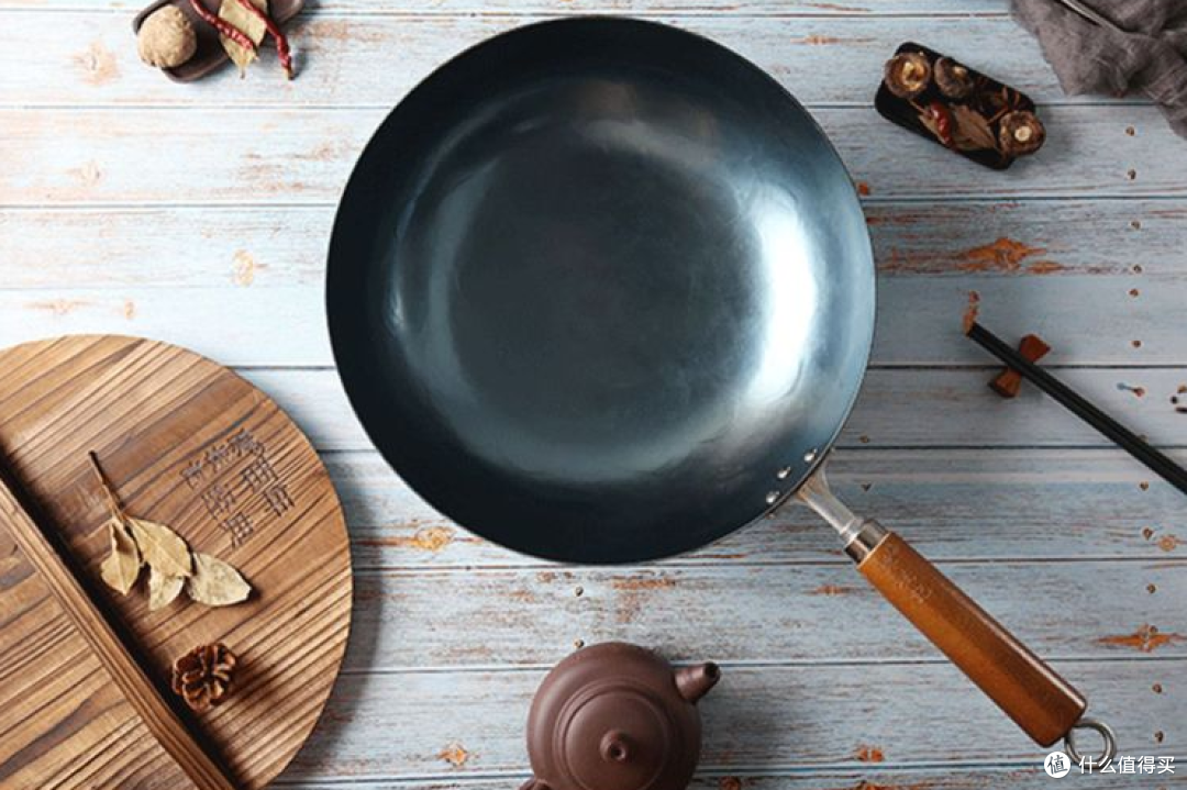 一张木质餐桌上的大铁锅盛满炖菜,锅中可见层层叠叠的白菜、琥珀色五花肉片和半透明红薯粉条,汤汁浓稠红亮,周围点缀着绿色葱花,背景虚化的餐桌上摆放着米饭碗和筷子 成品大锅白菜猪肉炖粉条全景图