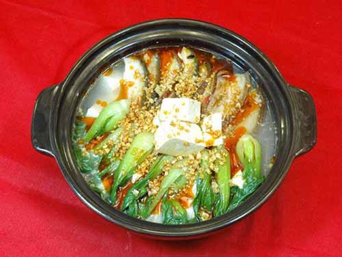 一口浅灰色陶瓷砂锅中盛满黄白菜炖豆腐,汤色清亮微黄,白菜舒展,豆腐块分明,表面漂浮着葱段与油花,背景为冬日窗台,窗外有雪花飘落,营造温暖治愈感 黄白菜炖豆腐砂锅全景