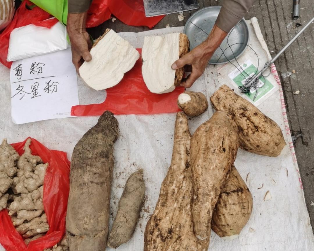 市场摊位上摆放多种类似芋头的根茎类蔬菜