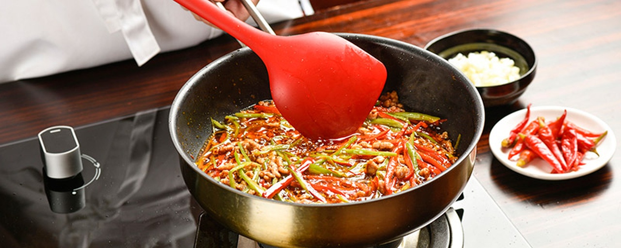 厨师正在铁锅中翻炒加入大量小红椒的菜肴,火焰升腾,锅中食材色泽红亮,充满烟火气,展现小红椒在热炒中的应用 小红椒入菜烹饪场景