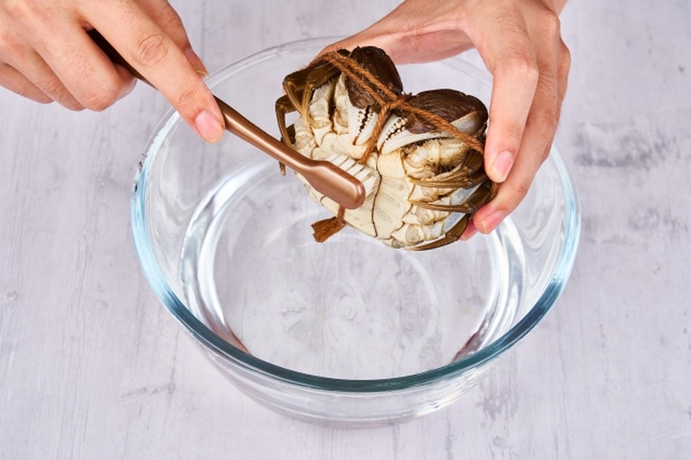 多只鲜活大闸蟹被放置于透明玻璃盆中,清水淹没一半蟹身,背景为厨房台面,光线柔和,展现大闸蟹在清水中吐沙的过程 大闸蟹在清水中吐沙静养