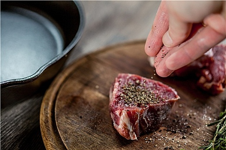 厨师正在使用手动胡椒研磨器研磨黑胡椒