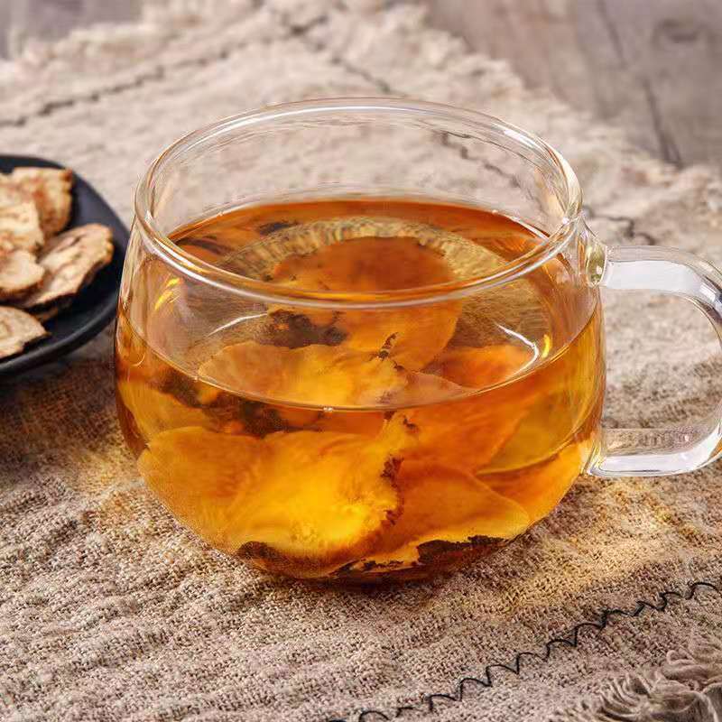 玻璃茶壶中正在冲泡北柴胡与其他中药材混合的茶饮,液体呈淡黄色透明状,上方升起袅袅热气,旁边摆放原始药材样品,整体画面温暖自然,突出健康养生氛围 北柴胡代茶饮冲泡过程展示图