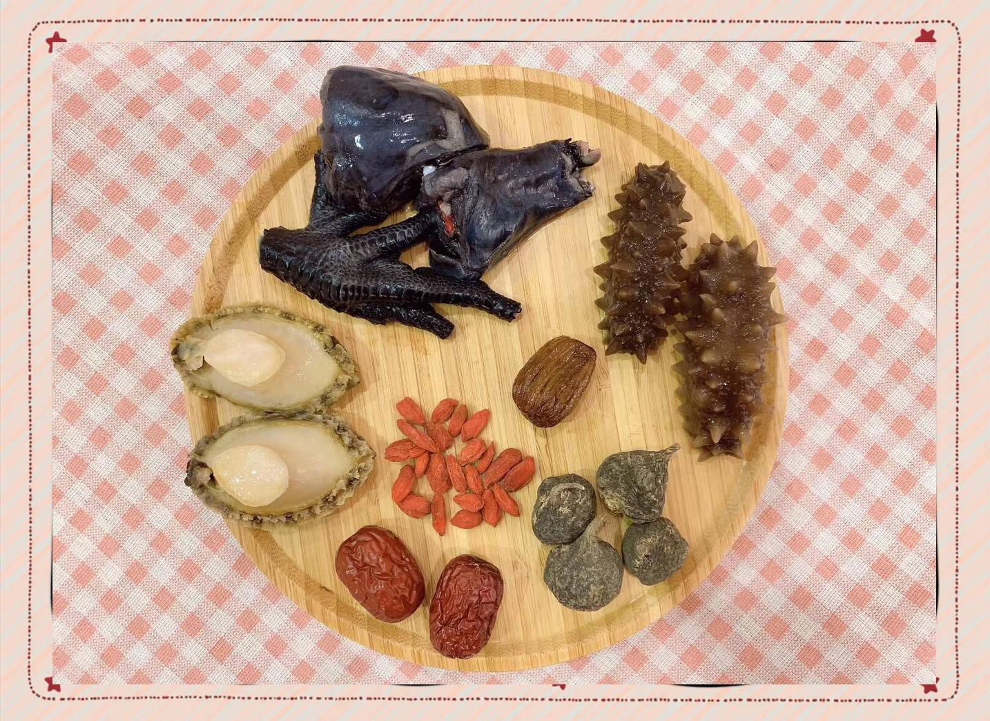 桌面上整齐摆放着泡发前的干海参两条、黑色饱满的干黑豆一小碗、新鲜姜片三片、枸杞若干,背景为木质砧板与陶瓷碗,光线柔和自然,突出食材原始质感 干海参与黑豆原料摆放图