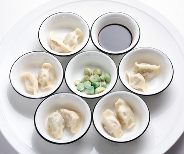 高清俯拍:展示饺子饱满形态与透光质感,强调‘皮薄不破、馅满不漏’,蘸碟中蒜泥醋汁色泽清亮,强化家常烟火气 刚出锅的萝卜猪肉饺子特写:晶莹饺子皮微透,隐约可见金黄肉粒与浅黄萝卜丁,热气氤氲,蘸碟中盛有蒜泥醋汁