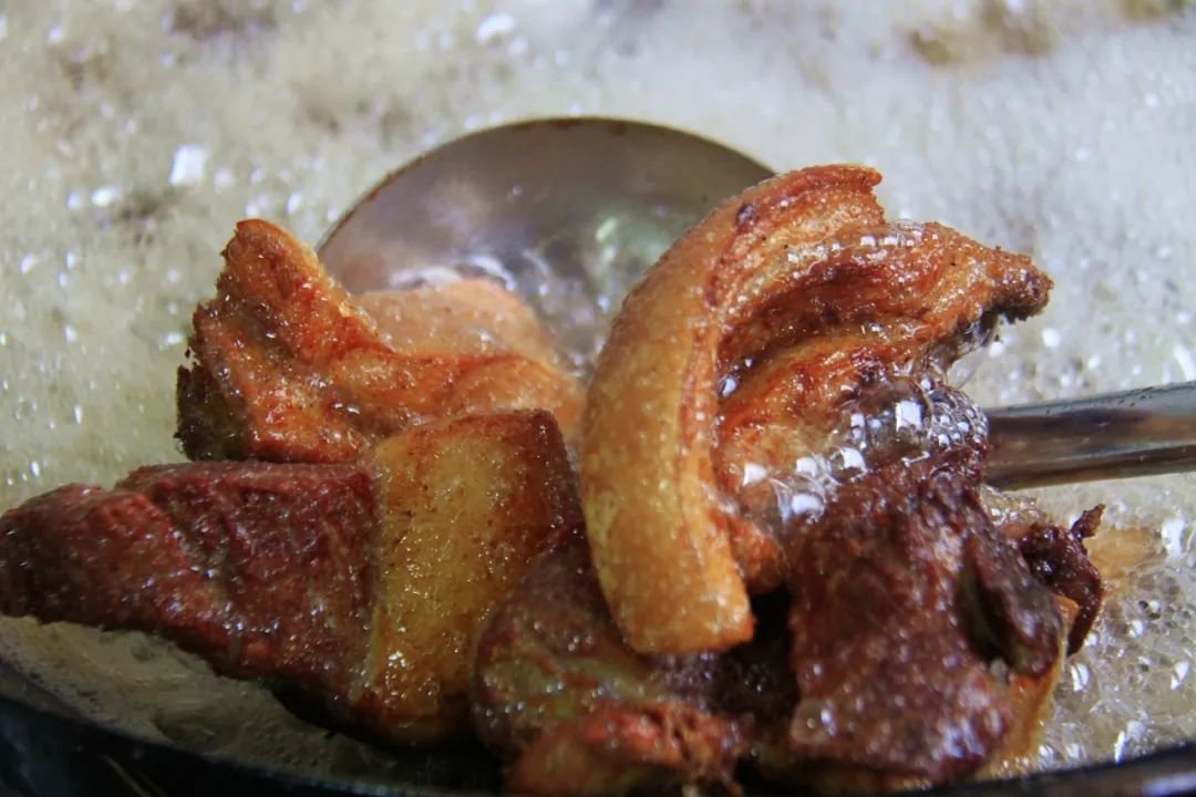 五花肉正在油锅中炸制,表面泛起金黄色气泡,香气四溢 五花肉正在油锅中炸制,表面泛起金黄色气泡