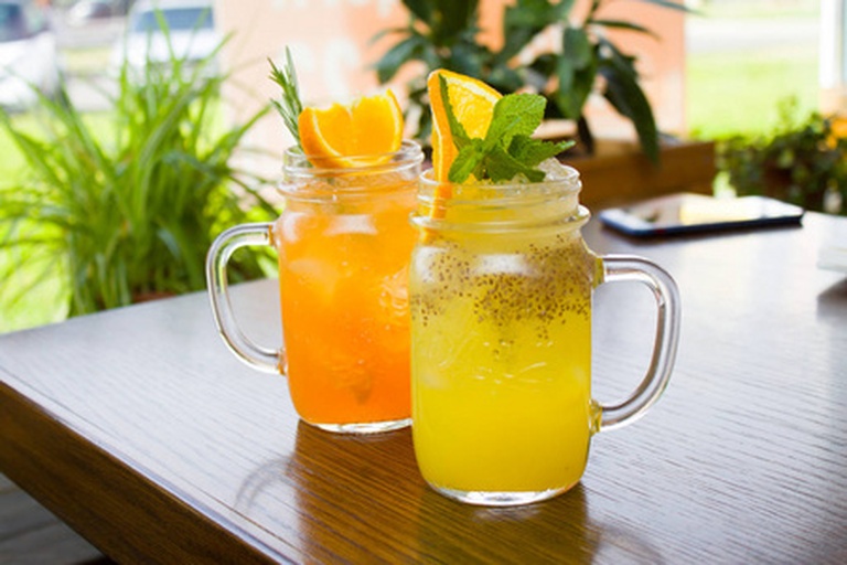 一杯鲜榨橙汁搭配两瓣完整橙子置于早餐桌上