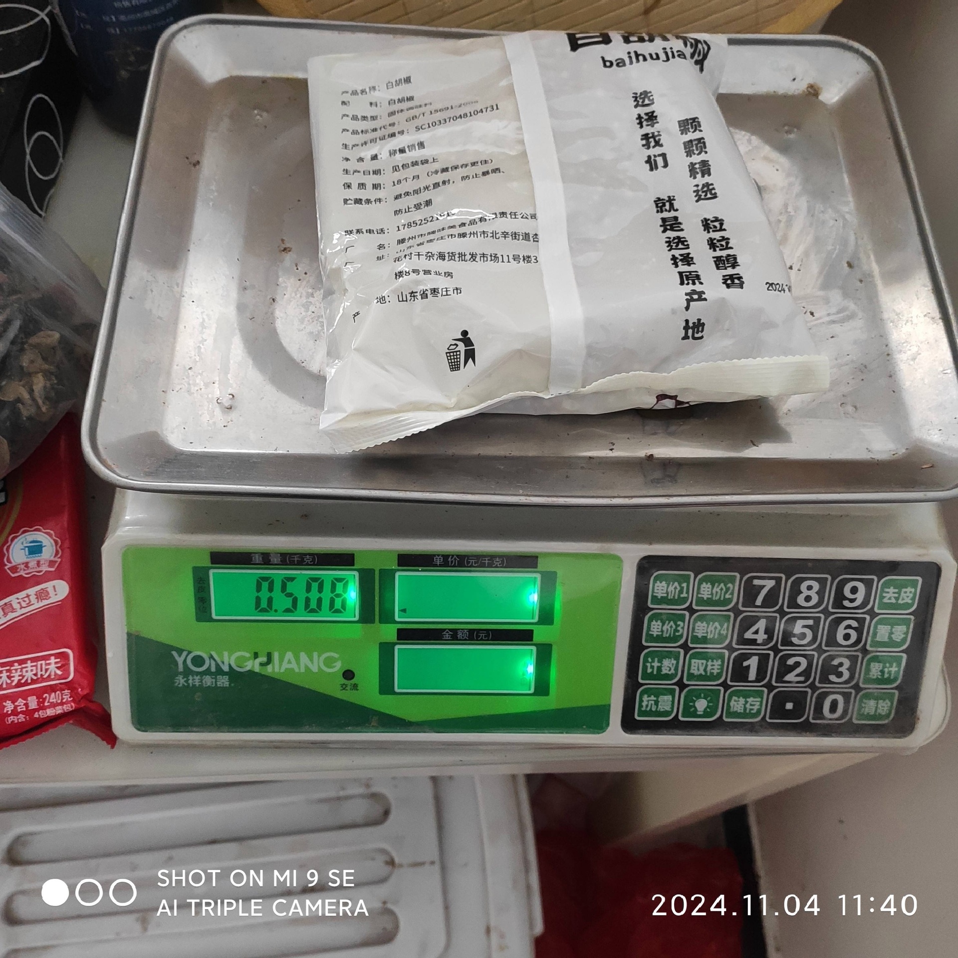 一台电子厨房秤显示20.0克读数,秤盘上整齐摆放约110粒完整的干红花椒,旁边另有一小堆碎屑状花椒用于对比,背景为白色瓷砖台面,突显精准称量场景 厨房秤与花椒对比图