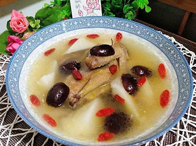 一碗热气腾腾的三七炖鸡脚盛放在白色瓷碗中,汤色呈淡金黄色,鸡脚饱满软糯,表面泛着油光,点缀几粒枸杞与红枣,背景虚化的木质餐桌营造温馨氛围 三七炖鸡脚成品汤品特写