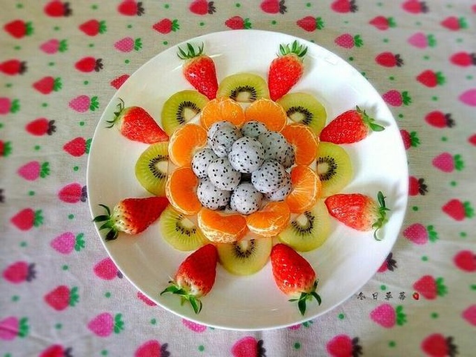 一张白色大理石餐桌上,中央摆放一颗完整的火参果,周围环绕切片的猕猴桃、蓝莓、橙子和薄荷叶,形成色彩丰富的水果拼盘,背景虚化,突出主题果实,传达健康饮食的生活方式 火参果与其他果蔬搭配摆盘图