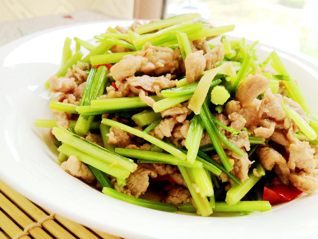 西芹与猪肉馅等原材料整齐摆放在木质案板上，背景为厨房环境，光线柔和自然