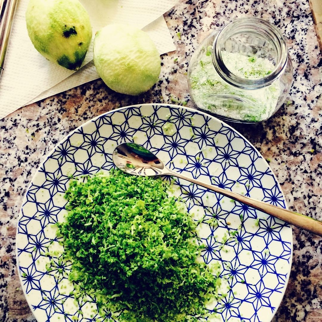 青柠盐渍果皮酱核心工序特写:左侧石臼内为青柠皮茸与海盐混合捣压状态,可见木杵下渗出浅黄色芳香油脂;右侧小瓷碗盛放漂洗控水后的皮茸,颗粒分明、湿润反光、无明水聚集;背景为消毒玻璃罐与青柠汁量杯,体现专业腌渍场景 青柠盐渍果皮酱制作:石臼中青柠皮茸与粗海盐混合,木杵正在捣压,皮茸泛出晶莹油光;旁边小碗盛放漂洗后的青柠皮茸,质地湿润蓬松,无水滴下