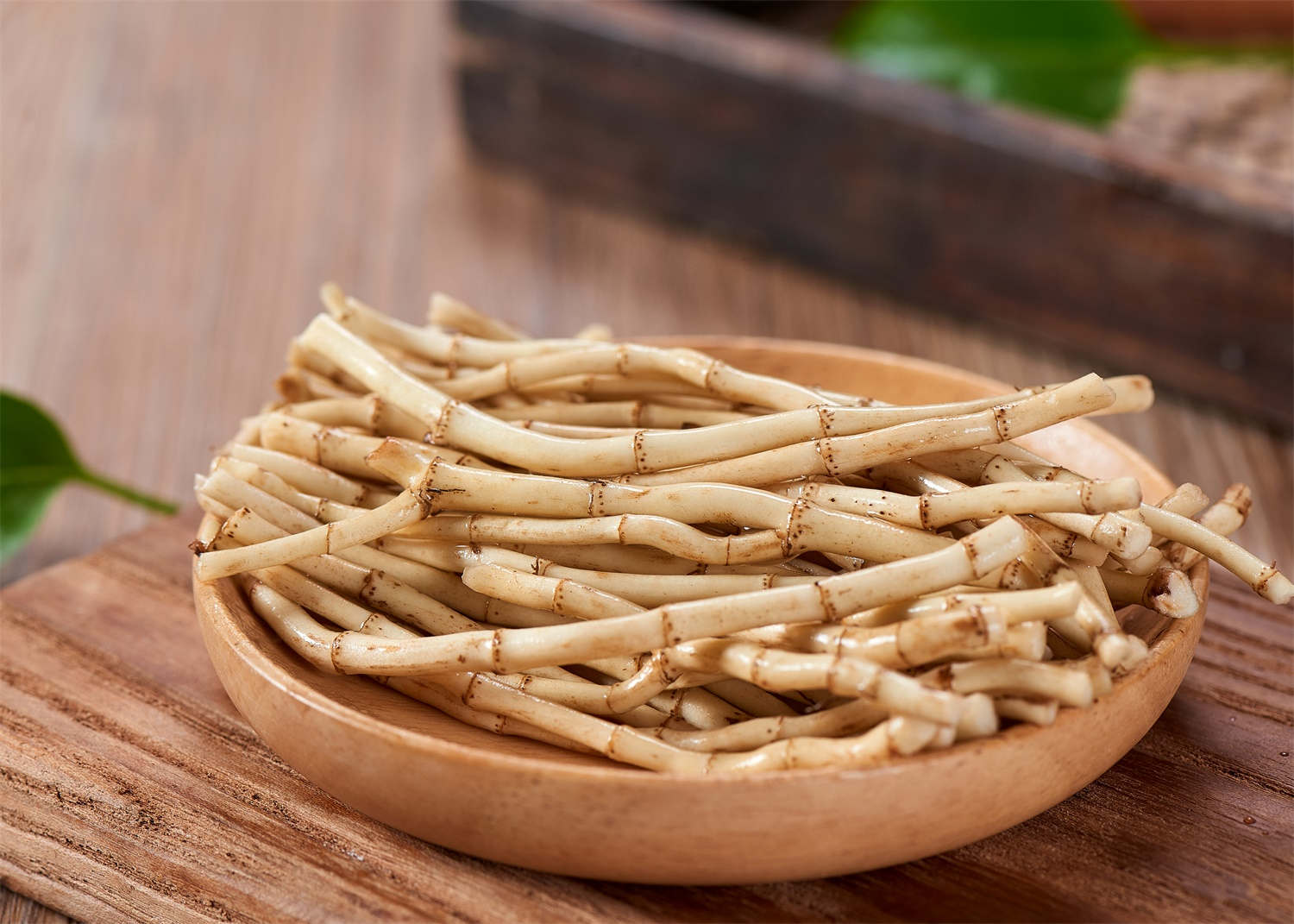 一盘焯水后的白色竹笋片摆放在木制餐盘中