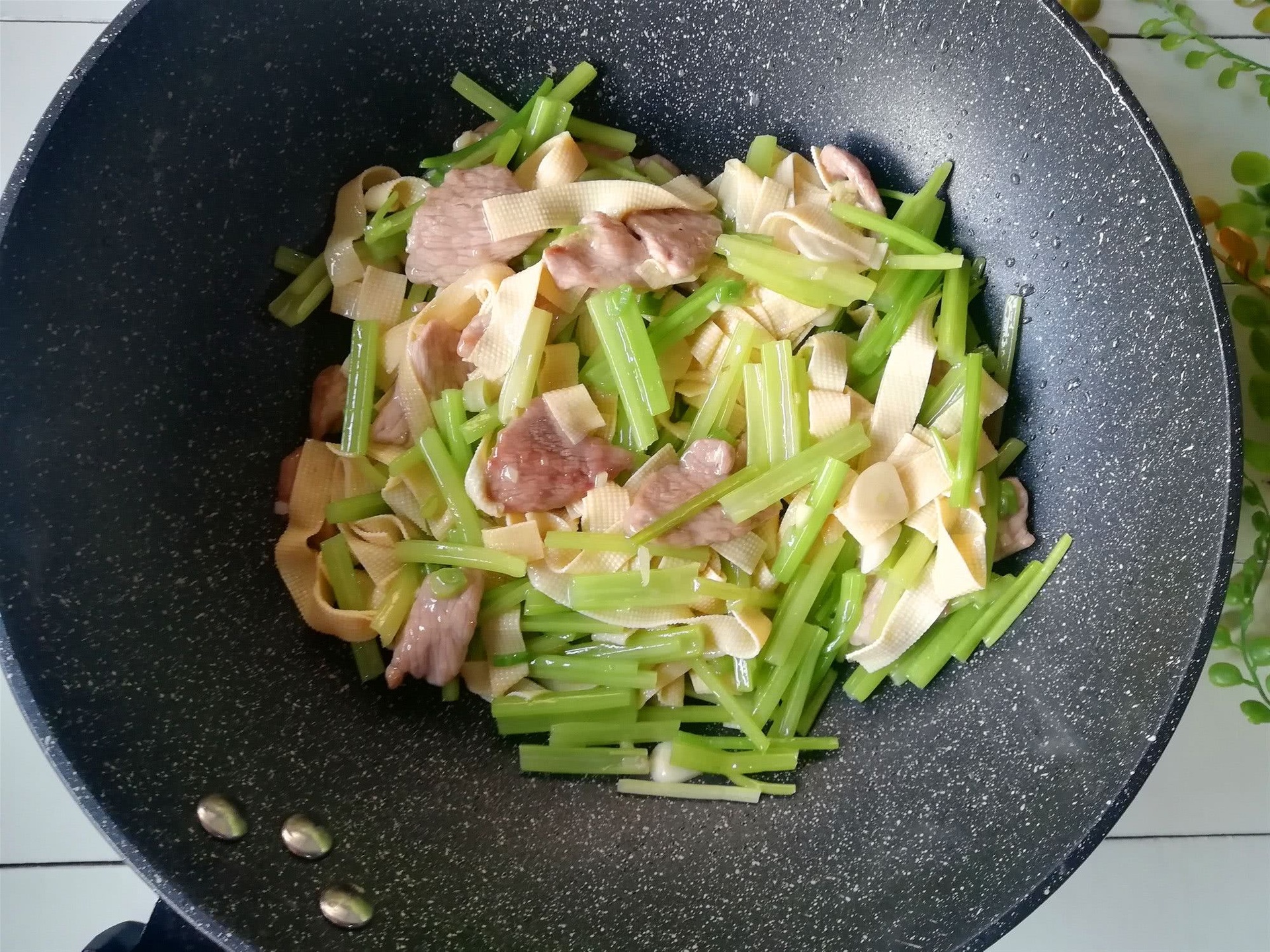 家庭厨房中式炒锅翻炒山芹与姜丝的烹饪过程