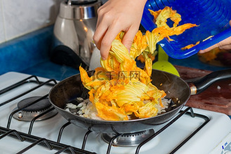 孕妇在厨房挑选南瓜花,准备制作健康菜肴,背景温馨自然 孕妇厨房准备食材场景